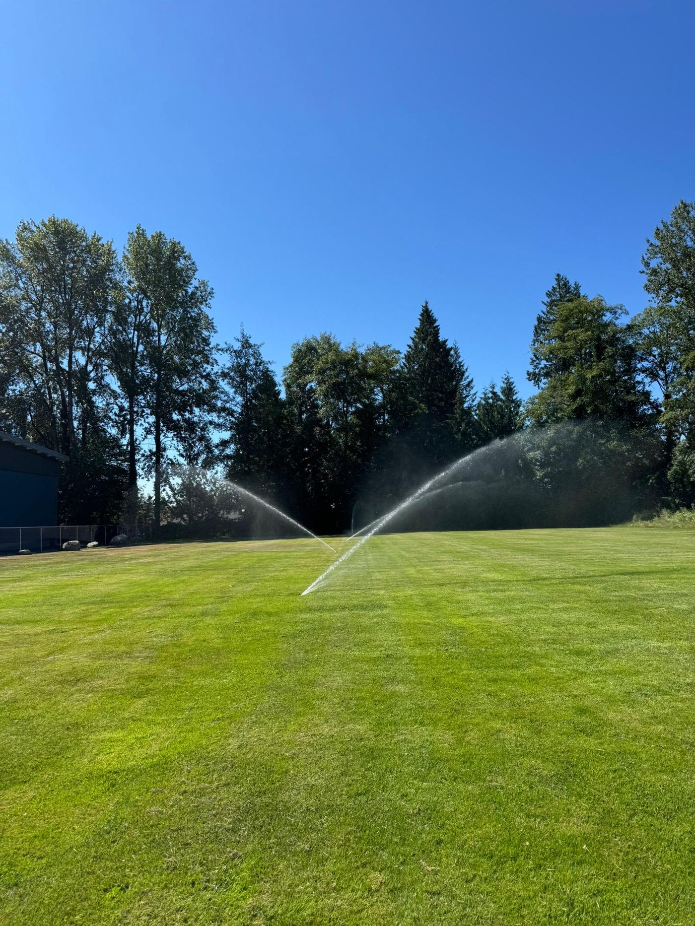 Irrigation sprinklers running on a lush green lawn in Vancouver